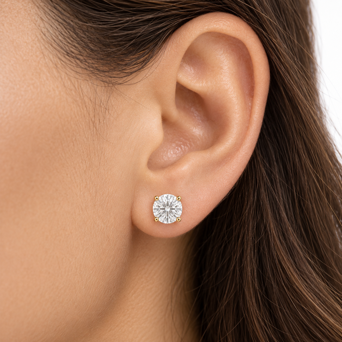 Round diamond stud earring worn on an ear, showing scale.