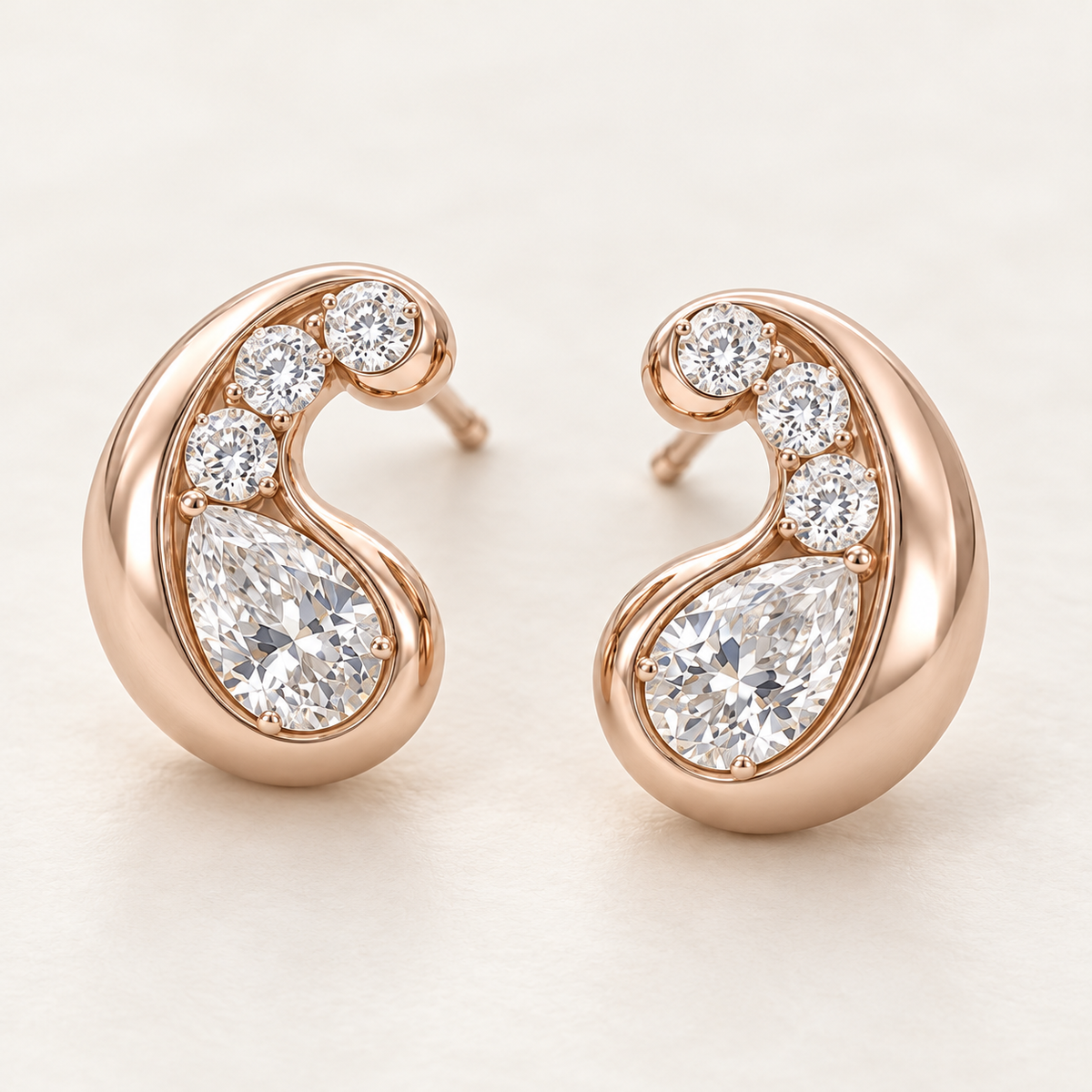 MISSISSI AA13 paired earrings in pale rose gold tone, three quarter view showing mirrored rounded comma-shaped curls around pear-shaped diamonds, with three round diamond accents per earring; design visualization