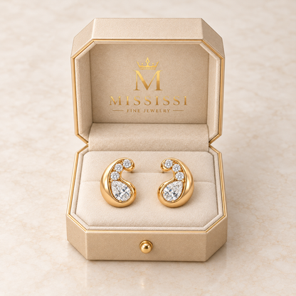 MISSISSI Satin Curl pear lab-grown diamond stud earrings in yellow gold, presented as a pair in champagne octagonal packaging with crown M branding; design visualization.