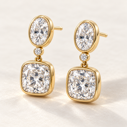 MISSISSI AA14 paired earrings in yellow gold tone, three quarter view showing an oval diamond above one small round connector diamond and a cushion-shaped drop in rounded bezels; design visualization