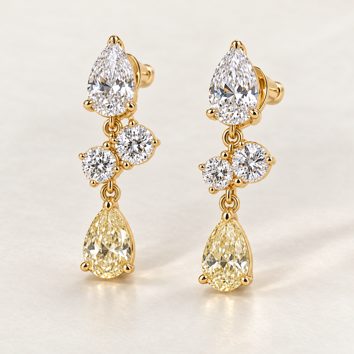 MISSISSI AA20 paired earrings in yellow gold tone, three quarter view showing a white pear-shaped diamond above two diagonally arranged round diamonds and a pale-yellow pear-shaped drop; design visualization
