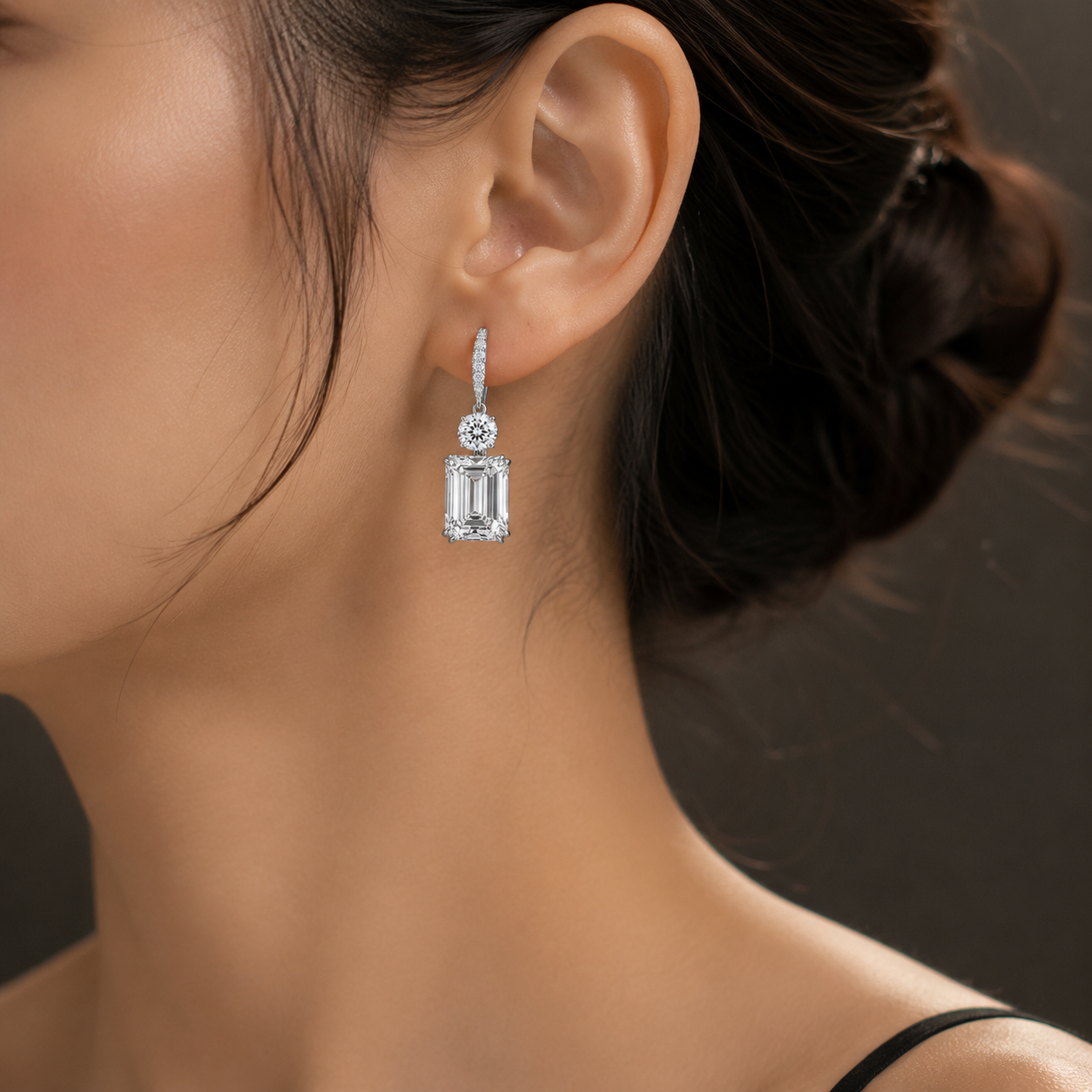 Front view of emerald cut diamond drop earrings with round brilliant diamond accents