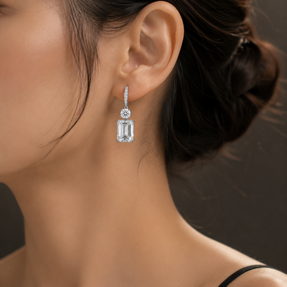 Front view of emerald cut diamond drop earrings with round brilliant diamond accents