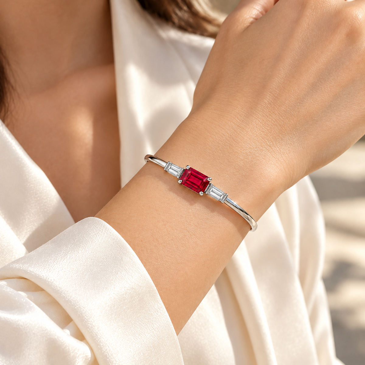 MISSISSI H26-RB02 white gold bangle with an east-west emerald-cut lab-grown ruby and two baguette lab-grown diamonds. Natural wrist wearing visualization.; design visualization