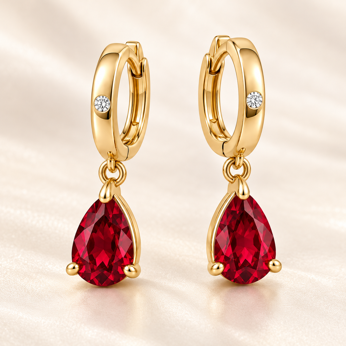 Three-quarter view of RE05 yellow gold huggies with permanently linked pear-shaped ruby drops; design visualization