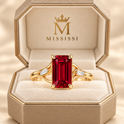 MISSISSI Crimson Ribbon lab-grown ruby ring in yellow gold with two baguette lab-grown diamond accents, champagne octagonal packaging visualization.