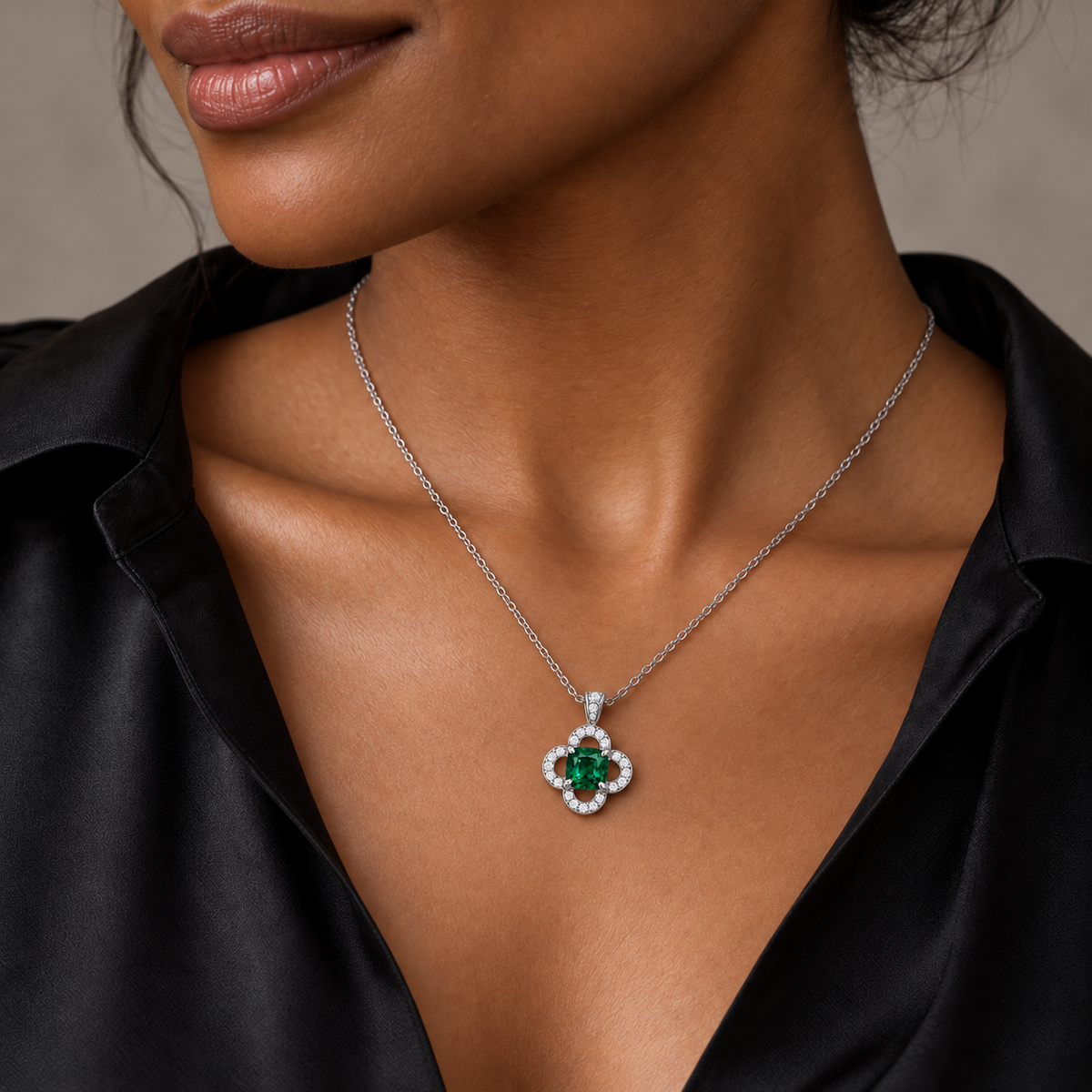 MISSISSI CLOISTER cushion lab-grown emerald quatrefoil necklace in white metal, shown on an adult model with deep warm brown skin; AI-generated wearing design visualization.