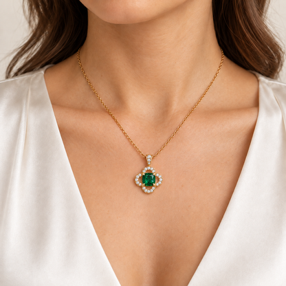 MISSISSI CLOISTER cushion lab-grown emerald quatrefoil necklace in yellow gold, shown on an adult model with light warm skin; AI-generated wearing design visualization.