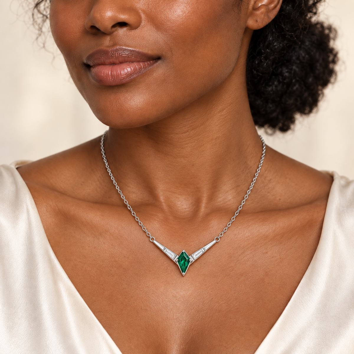 Design visualization of an adult model wearing the EM27 Chevron necklace in white metal, with an integrated kite lab-grown emerald and two baguette lab-grown diamonds.