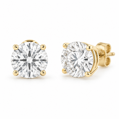 Matched pair of round diamond stud earrings in four-prong yellow gold settings.