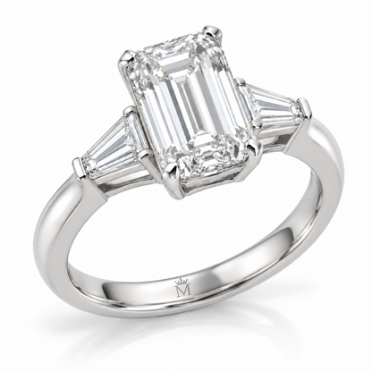 AI-generated design concept: Emerald cut ring, Prong-set center with two tapered baguette side stones, three-quarter view. Metal appearance is illustrative. Crown-M engraving design is shown inside the lower band; engraving is illustrative.