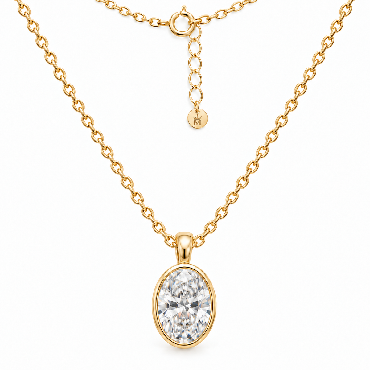 Oval lab-grown diamond bezel pendant on a fine gold chain, arranged on white. AI-edited crown-M engraving concept on the existing extender end disc; engraving and scale are illustrative.