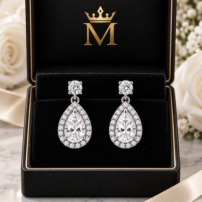 Cora pear halo drop earrings in 14K white gold, displayed in an open black jewelry box. Design visualization.