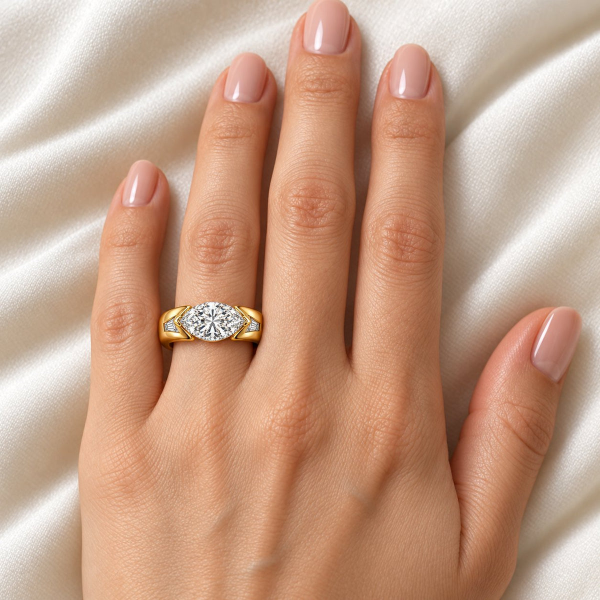 Marquise Horizon yellow-gold design with an east-west marquise center and tapered baguette accents worn on an adult model's ring finger; design visualization with illustrative scale