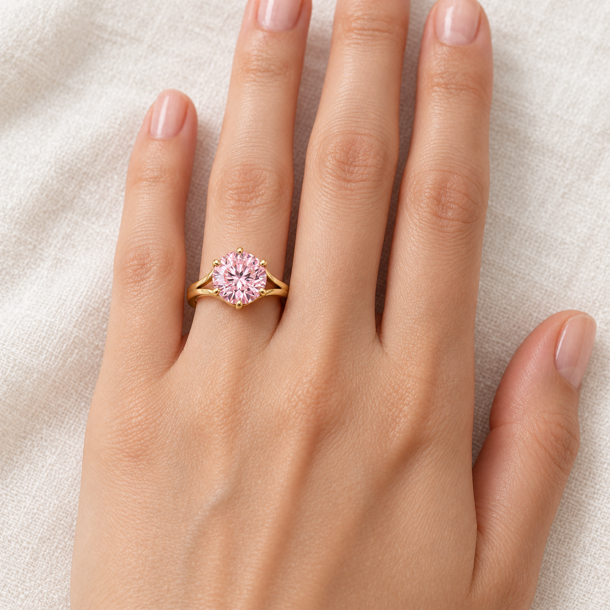 MISSISSI Blush Bloom pink round brilliant lab-grown diamond ring with six claws and open yellow-gold arch shoulders, worn on the left ring finger