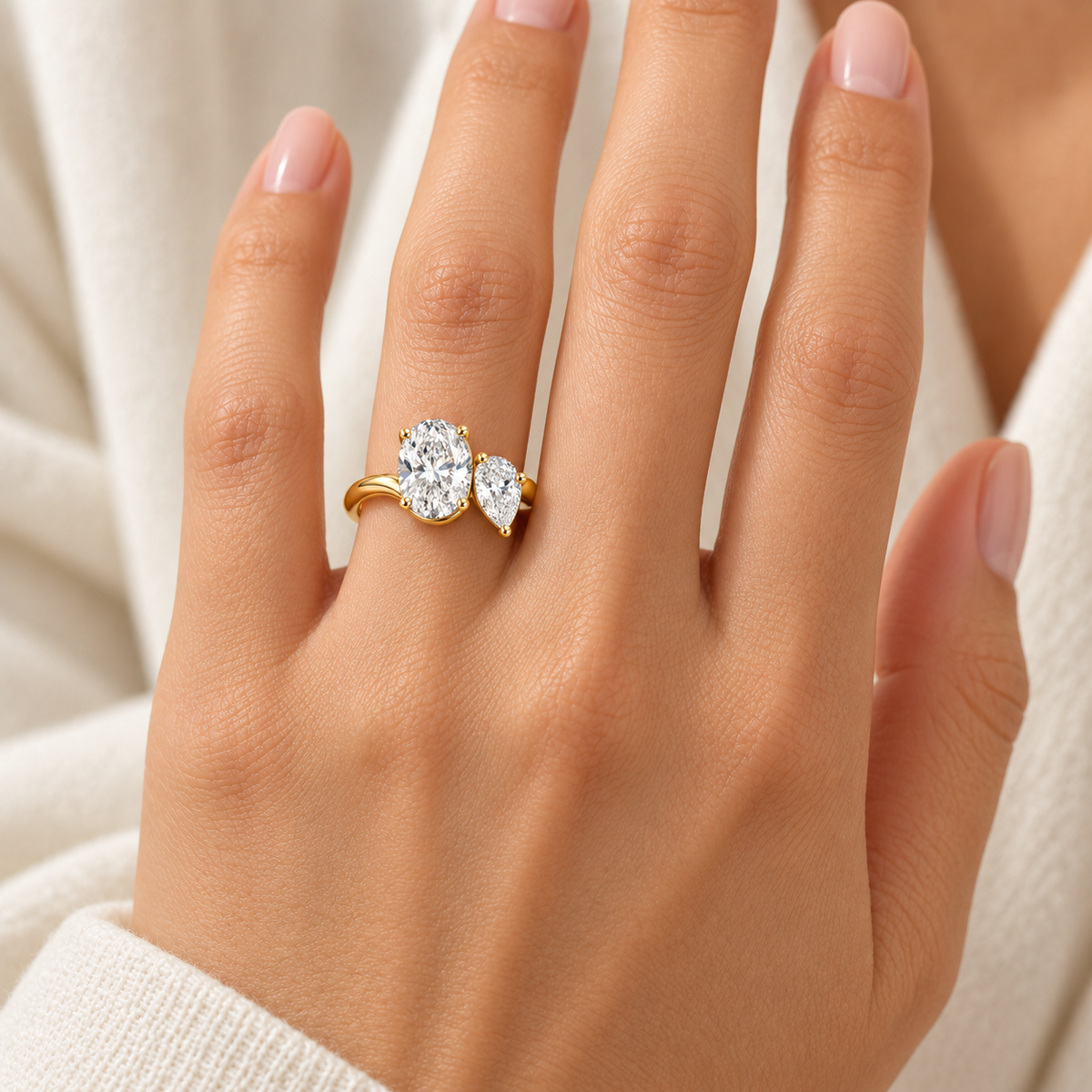 Near Oval and Pear Lab-Grown Diamond Ring on an adult hand, showing connected gold shoulders and a continuous shank; AI-generated design visualization