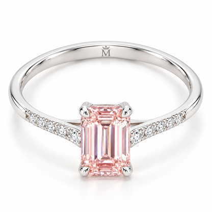 Tilted AI view showing the slender pink emerald-cut ring and a discreet crowned-M engraving inside the lower shank.