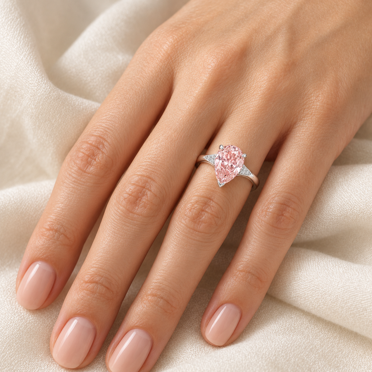 AI-generated on-hand design visualization of the Rosadew pear pink lab-grown diamond ring in white-gold appearance; illustrative fit and scale.