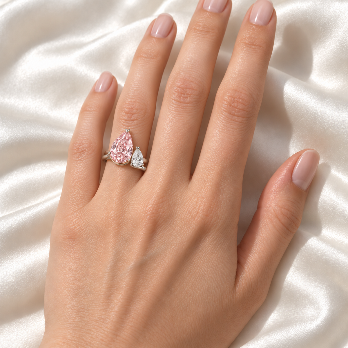 AI design preview of Rose Dialogue pink and white pear ring on an adult left ring finger; scale illustrative