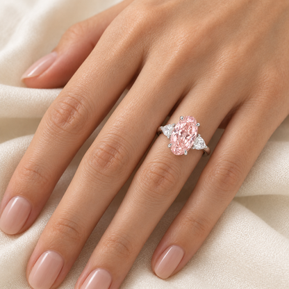 AI on-hand visualization of Rosemere's elongated oval pink lab-grown diamond ring with pear-shaped white side stones in white gold; scale is illustrative.