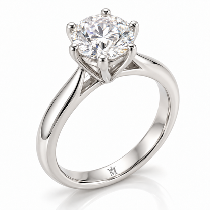 AI-generated design concept of a round diamond-style six-prong solitaire ring in white-tone metal, three-quarter view. Crown-M engraving design is shown inside the lower band; engraving is illustrative.