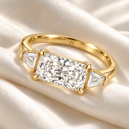 MISSISSI U03 east-west radiant lab-grown diamond three-stone ring in yellow gold, ring resting on ivory fabric; design visualization