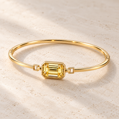 MISSISSI YB09 yellow diamond bezel bangle, three-quarter view on ivory limestone. Design visualization.