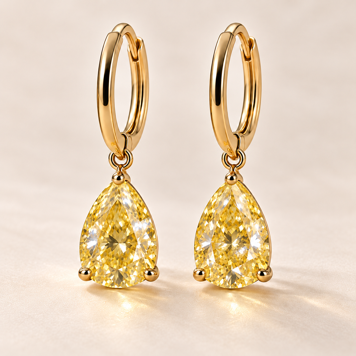 Design visualization of pear-shaped lab-grown yellow diamond drops suspended point-up below slim huggie-style hoops
