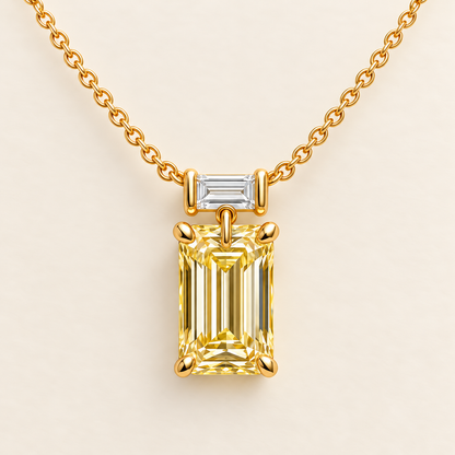 Design visualization of a vertical emerald-cut lab-grown yellow diamond pendant below a horizontal baguette-cut lab-grown diamond on a chain