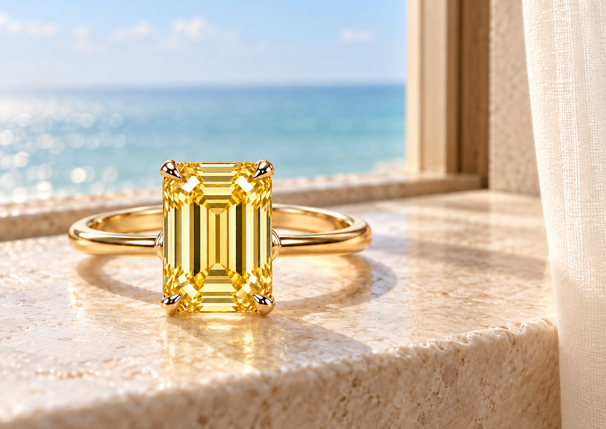 MISSISSI YR02 vertical emerald-cut lab-grown yellow diamond ring beside a sunlit window with a softly blurred sea view; design visualization