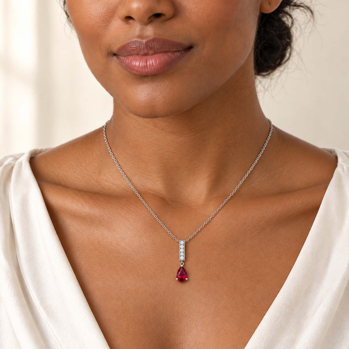 Design visualization of an adult model wearing the RB28 Ruby Line necklace in white metal, with a slim diamond baton and point-up pear lab-grown ruby.