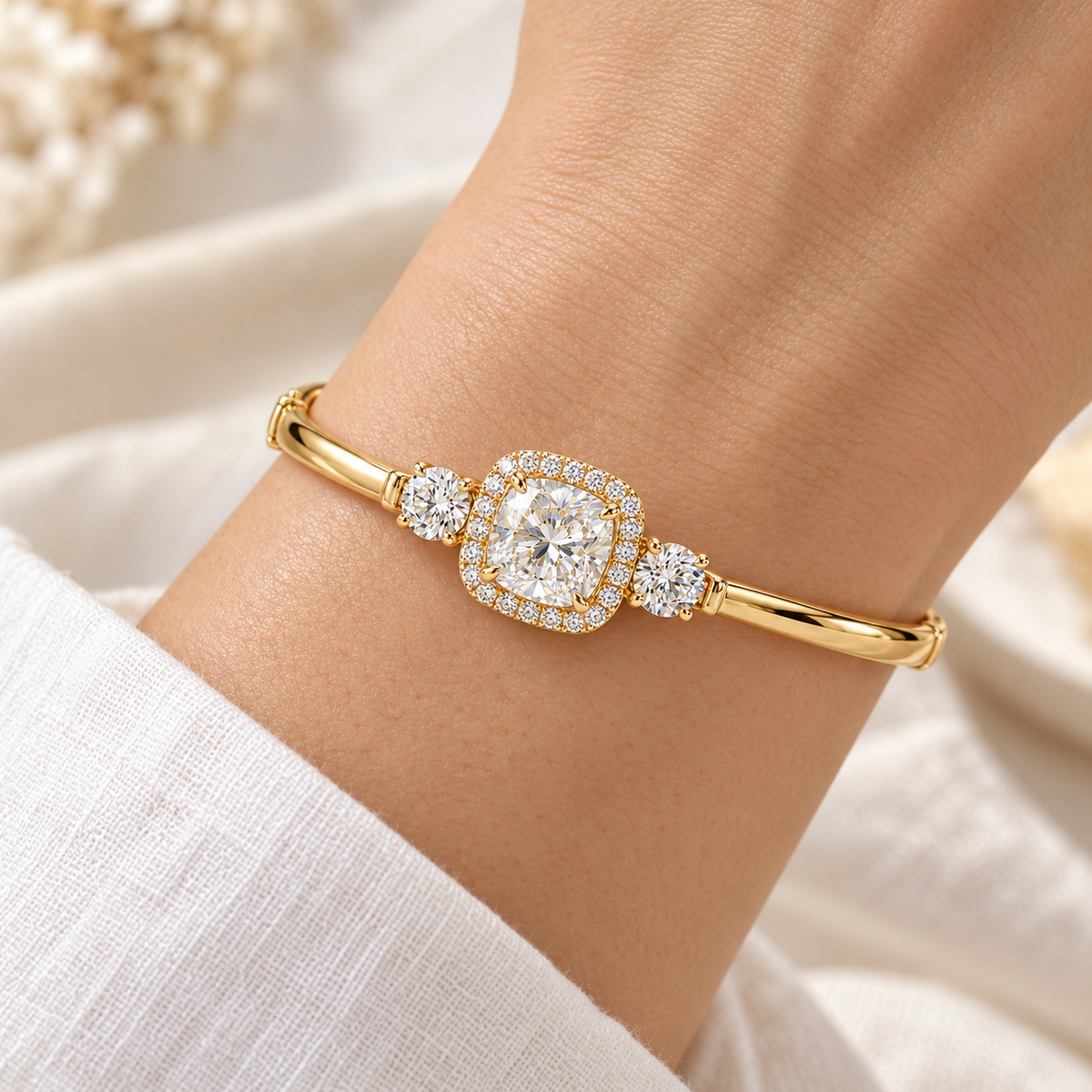 MISSISSI U11 cushion-cut lab-grown diamond halo closed oval bangle in 14K yellow gold, adult wrist worn view, with one round diamond on each shoulder.