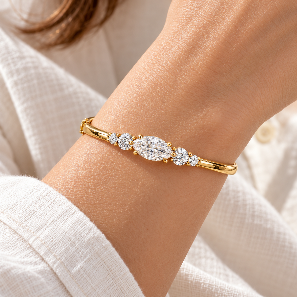 MISSISSI U12 east-west marquise-cut lab-grown diamond closed oval bangle in 14K yellow gold, adult wrist worn view, with two graduated round diamonds on each shoulder.