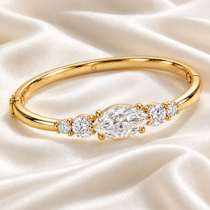 MISSISSI U12 east-west marquise-cut lab-grown diamond closed oval bangle in 14K yellow gold, ivory silk still life, with two graduated round diamonds on each shoulder.